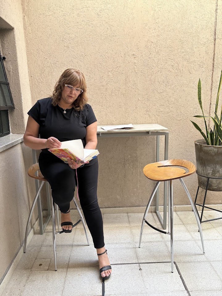 Carina Cazzoli leyendo un cuaderno en el patio